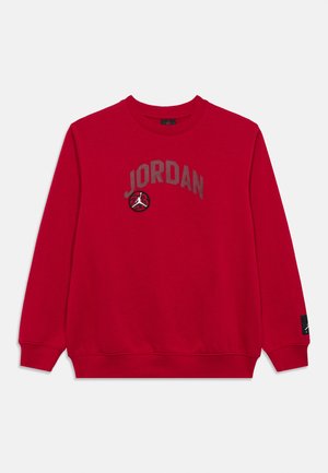 Punane pikalõuaga dressipluus, millel on ees "JORDAN" tekst ja korvpallimärk ning varrukal väike must logo.