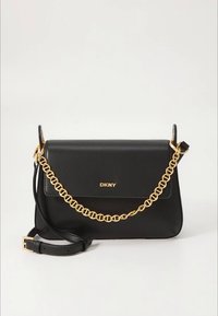 Svart läderhandväska med övervikningsklaff, guldkedjestrap, DKNY-logotyp och slät textur. Har en avtagbar axelrem.
