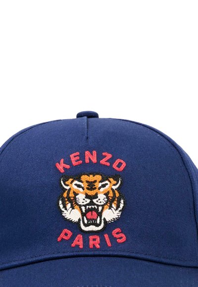 Marineblauwe pet met een geborduurd brullend tijgerhoofd, met "KENZO" erboven en "PARIS" eronder in rode letters.