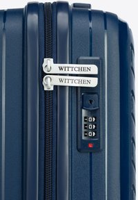 Navy hardshell suitcase with dual zippers, silver hardware, combination lock, and textured surface for durability. Brand name displayed.