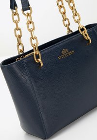 Sac en cuir bleu marine avec une finition texturée, doté de poignées en chaîne dorée, et d'un logo WITTCHEN sur le devant.