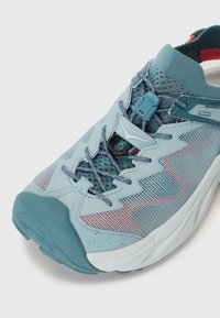 Baskets de sport bleu clair avec un matériau en maille, des accents roses contrastants et un système de laçage sécurisé. Bout arrondi et semelle texturée.