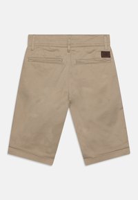 Pantaloni cargo color khaki con una superficie liscia, dotati di due tasche posteriori e un'etichetta in pelle sulla vita. Design sartoriale e lunghezza al ginocchio.