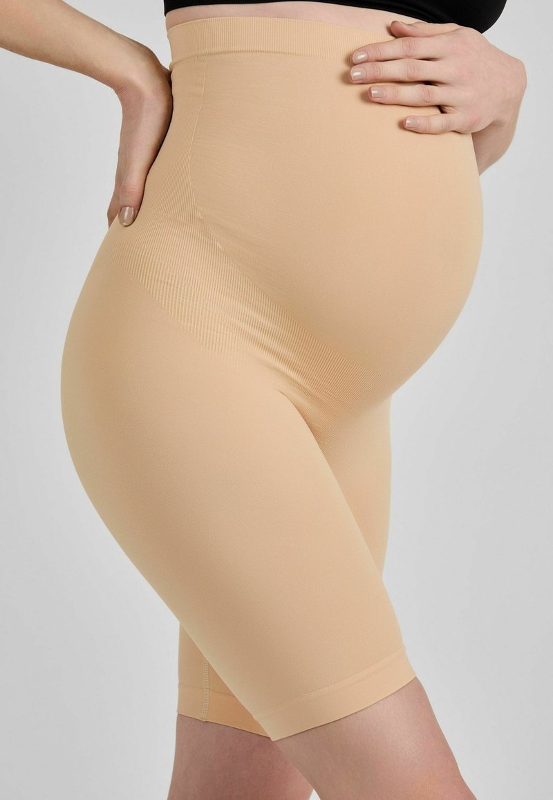 Pantaloni scurți de maternitate bej, cu talie înaltă și design până la genunchi. Construiți dintr-un material neted și elastic, cu nervuri subtile pe laterale.
