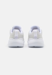 Bílé tenisky s texturovaným pleteným svrškem, polstrovaným límcem a odpruženou podrážkou. Mají hladký, minimalistický design s poutkem na patě.