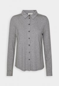 Chemise grise à manches longues avec col pointu, sept boutons sur le devant et un ourlet légèrement incurvé.