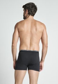Black boxer briefs made from cotton with a fitted design. Features a contrasting waistband with branding and a smooth texture.