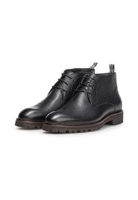 Botas de tobillo de cuero negro con un acabado texturizado, diseño de cordones y suela de goma resistente. Asa en la parte trasera para facilitar el calzado.