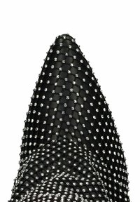 Chaussure à talon aiguille noire avec un bout pointu, présentant une surface texturée ornée de clous en argent disposés en motif de grille.