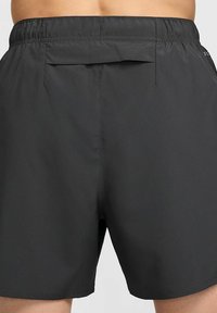 Schwarze Sportshorts aus leichtem Stoff. Mit elastischem Bund und Tasche auf der Rückseite. Glatte Textur und Länge über dem Knie.