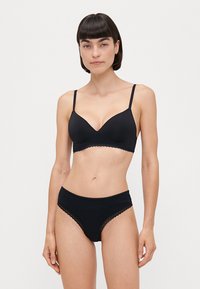 Black lingerie set featuring a soft, padded bralette with adjustable straps and scalloped lace detail, paired with matching high-waisted panties.