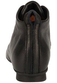Botte de cheville en cuir noir avec une texture lisse, un bout arrondi et une couture à l'arrière, dotée d'un petit talon.
