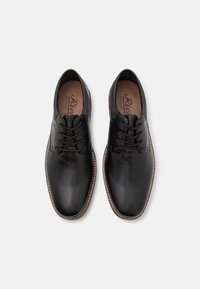 Scarpe eleganti in pelle nera con una finitura liscia, punta rotonda, design con lacci e cuciture a contrasto lungo la suola.