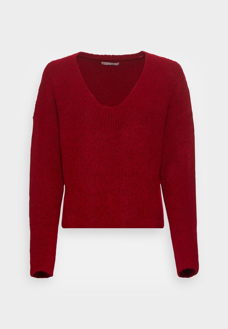 Pull en maille rouge à manches longues avec col en V et texture côtelée, présenté sur un fond blanc uni.