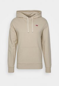 Beige hette laget av mykt stoff, med kengurulomme, justerbar snøring og en liten rød Levi's-logo på brystet.