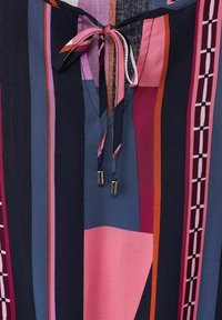 Multicolored top featuring vertical stripes in navy, pink, and burgundy. It has a tie closure with metal tips and a soft fabric texture.