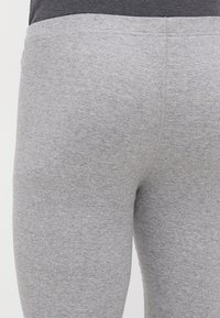 Szürke bordázott leggings jól illeszkedő fazonnal, sima textúrával és egyszínű megjelenéssel, amely a bokaig ér.