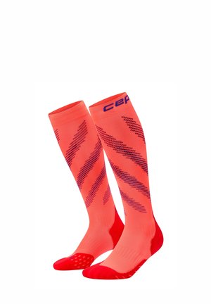 Helle orangefarbene kniehohe Kompressionssocken mit diagonalen dunklen Streifen sowie roten verstärkten Zehen und Fersen.