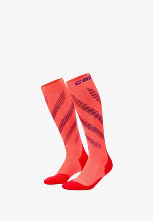 Helle orangefarbene kniehohe Kompressionssocken mit diagonalen dunklen Streifen sowie roten verstärkten Zehen und Fersen.