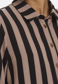 Camicia con bottoni caratterizzata da strisce verticali nere e rosa chiaro, colletto e dettagli in bottone dorato, realizzata in un tessuto testurizzato.