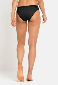 Bas de bikini noir avec une texture lisse, couverture moyenne et une ceinture large. Le tissu semble extensible et moulant.