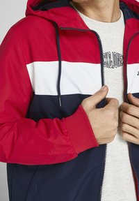 Rot, Weiß und Navy farbblockierte Kapuzenjacke mit Reißverschluss vorne, elastischen Bündchen und Kordelzug-Kapuze. Texturierter Stoff mit glatter Oberfläche.