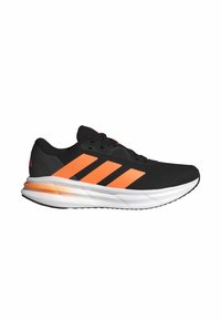 Zwarte sport schoenen met oranje accenten, bovenwerk van mesh, gestructureerd oppervlak en een gewatteerde witte zool, met drie oranje strepen aan de zijkant.