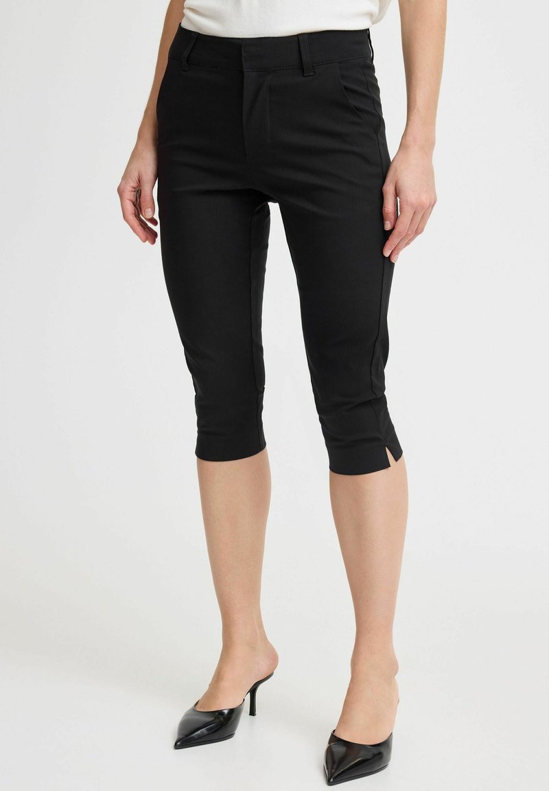 Schwarze, cropped Hosen aus einem glatten Stoff, mit schmaler Passform, seitlichen Schlitz am Saum und einer klassischen Taille.
