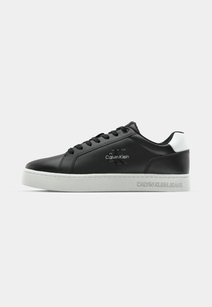 Sneaker in pelle nera con accenti bianchi e suola in gomma testurizzata. Le caratteristiche includono lacci, un logo sul lato e marchio sul tallone.