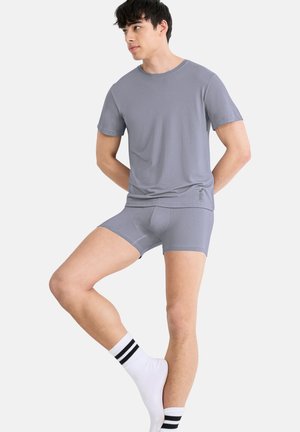 Grijs T-shirt met korte mouwen gecombineerd met grijze nauwsluitende boxershorts. Zachte stof met minimale naden, voorzien van een tailleband en subtiele branding.