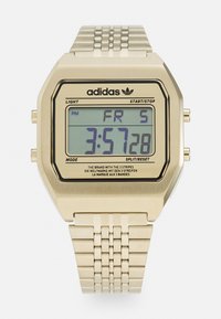Montre numérique avec un boîtier hexagonal en ton or. Elle dispose d'un affichage rétroéclairé en bleu, d'un bracelet en maillons métalliques et d'accents noirs autour du cadran.