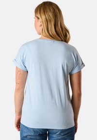 Maglietta a maniche corte blu chiaro, con una vestibilità rilassata e maniche arrotolate, realizzata in un tessuto morbido con una sensazione liscia.