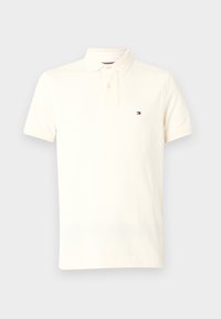 Polo à manches courtes de couleur crème avec deux boutons et un petit logo drapeau Tommy Hilfiger sur la poitrine gauche.
