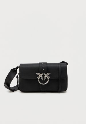 Sac en cuir noir à bandoulière avec une sangle réglable et un fermoir en argent, présentant deux oiseaux se faisant face sur un anneau.