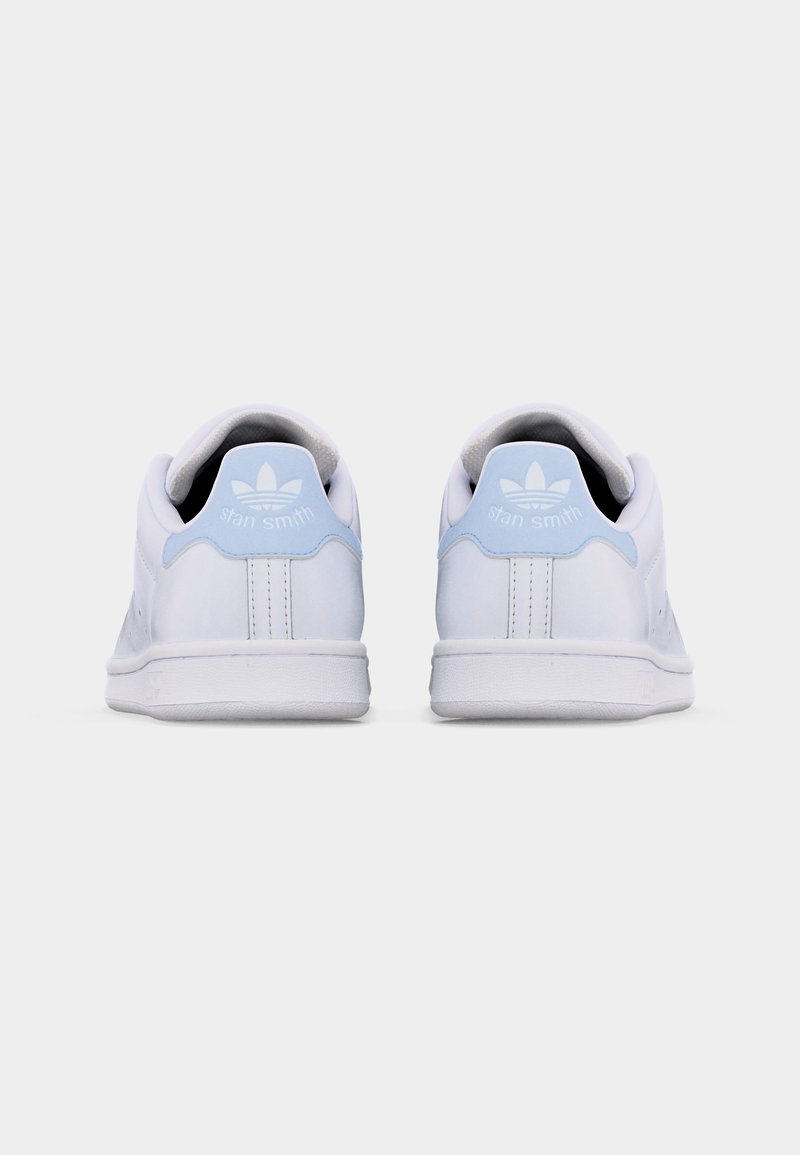 Par hvide Adidas Stan Smith-sneakers vist bagfra med lyseblå hælflapper med mærkets logo og tekst.
