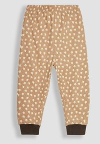 Pantalon marron pour enfants avec un motif répétitif de formes crème ressemblant à des feuilles. Il dispose d'une taille élastique et de poignets marron foncé.