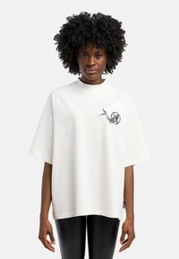 Witte oversized t-shirt met korte mouwen en hoge hals, voorzien van een kleurrijk geborduurd ontwerp van een slang op de linker borstpartij.