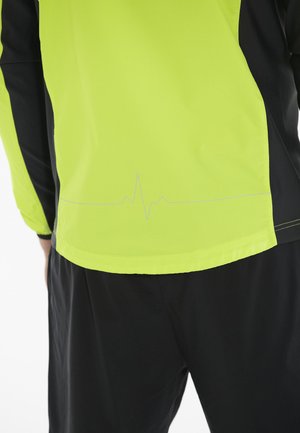 Leichte Jacke in leuchtendem Gelb mit schwarzen Akzenten. Hat ein Herzschlag-Muster, das nahe dem Saum aufgedruckt ist. Glatte Textur, sportliches Design.