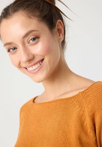 Suéter de punto en un cálido naranja, con un escote amplio, acabado texturizado y sutiles detalles de trenzado en el hombro.