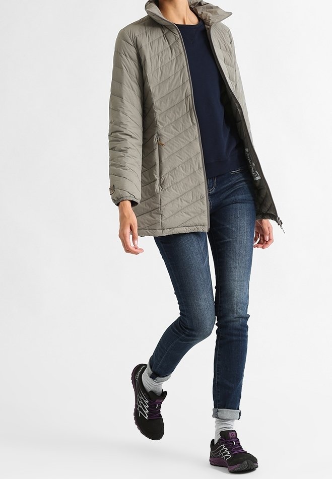 Light gray quilted jacket with a high collar, worn over a navy sweater. Paired with dark denim jeans and black athletic shoes with purple accents.