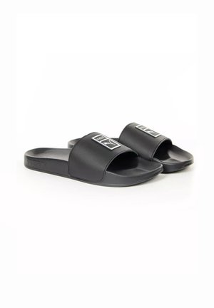 Paire de sandales noires Puma avec larges brides et logo Puma sur chaque bride, présentées sur fond blanc.