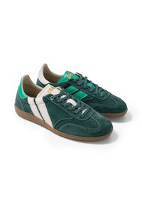 Paire de baskets en daim vert avec des bandes blanches, talon en cuir vert, semelle en gomme et lacets verts sur fond blanc.