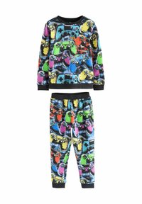 Fleece-pyjamasetti, jossa on värikkäitä peliohjaimia mustalla taustalla. Pitkät hihat ja elastiset housut mustilla resoreilla.