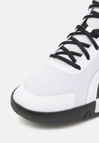 Sneaker bianco con tomaia in tessuto testurizzato, lacci neri e suola in gomma nera. Punta rotonda con accenti di design sottili.