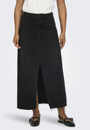 Jupe maxi en denim noir avec fente avant, ourlet effiloché et design à cinq poches. Portée avec des ballerines noires à clous. Texture lisse et structurée.