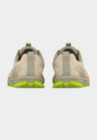 Ζευγάρι μπεζ και πράσινα παπούτσια για τρέξιμο σε μονοπάτια, που φαίνονται από πίσω, με ταινίες έλξης με την ένδειξη «GTR» και υφασμένα πέλματα.