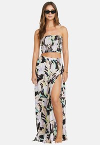 Completo floreale composto da due pezzi, con top cropped senza spalline e gonna maxi con uno spacco fino alla coscia. Base nera con motivi floreali dai colori chiari.