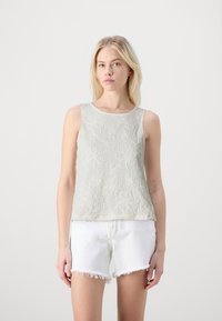 Top sin mangas de color gris claro con tejido texturizado y un sutil patrón floral, combinado con pantalones cortos blancos desgastados. Diseño minimalista.