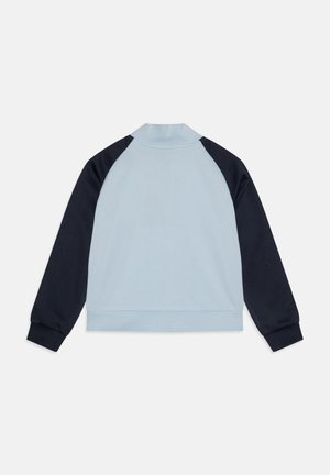 Pulover z dolgimi rokavi svetlo modre barve telesa in temno mornarsko modrimi rokavi, pokončni ovratnik, rebrasti manšete in pas, položen na ravno površino s hrbtno stranjo navzdol.