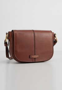 Borsa a tracolla in pelle marrone con chiusura a pattina, hardware in tono oro e dettaglio cucito ai bordi. Presenta un logo del marchio sul fronte.